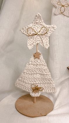 a white crocheted christmas tree on a wooden stand with gold stars and bows