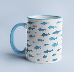 a blue and white coffee mug with fish on it's side, against a gray background