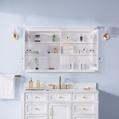 a bathroom with blue walls and white cabinetry, gold accessories on the counter top