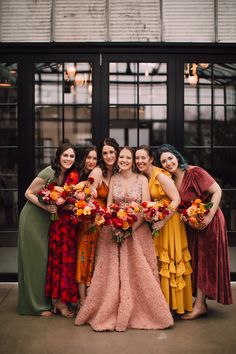 a group of women standing next to each other in dresses and holding bouquets on their laps