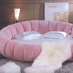 a round bed with fluffy pillows on the floor