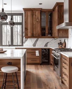 a kitchen with wooden cabinets and marble counter tops, an island in front of the stove