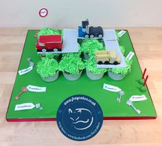 cupcakes with green frosting on top of a table topped with trucks and trees