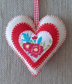 A handmade light beige felt heart decoration. The heart has been decorated with cotton and felt fabric hearts. All the pieces of material have been cut out by hand and sewn together using a blanket stitch. The heart is attached to a red checked ribbon. Size of heart excluding the ribbon is approx. 12cm x 12cm. Door Hanging Decorations, Cotton Decor, Fabric Hearts, Felt Heart, Handmade Lighting, Blanket Stitch, Heart Decorations, Door Hanging, Felt Fabric