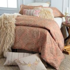 a bed with pillows and blankets on top of it next to a table in a room