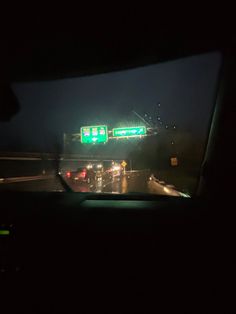 the view from inside a car looking at traffic lights and street signs in the dark