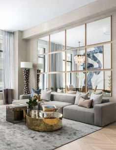 a living room filled with lots of furniture next to tall windows on top of a hard wood floor