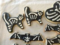 decorated cookies with black and white icing are arranged on a tablecloth in the shape of bats