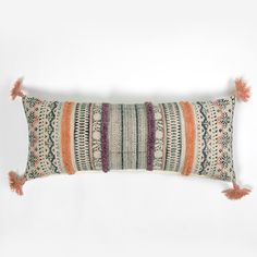 a decorative pillow with tassels and fringe on the front, sitting against a white background