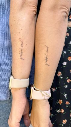 two people holding hands with tattoos on their arms