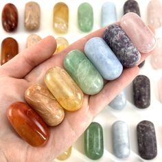 a hand holding five different colored rocks in it's palm next to each other