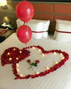 heart shaped bed with candles and balloons in the shape of a heart on top of it