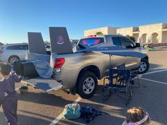 two children are standing in the parking lot next to a pickup truck with its tail lights on