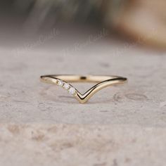 a gold ring with three small diamonds on the side, sitting on top of a rock