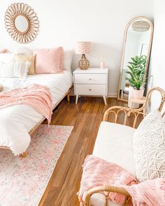 a bedroom with white walls and wooden floors is decorated in pastel pinks and whites