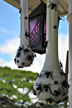 spider decorations hanging from the side of a white building with purple light in the background