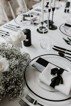 the table is set with black and white place settings, silverware, and flowers