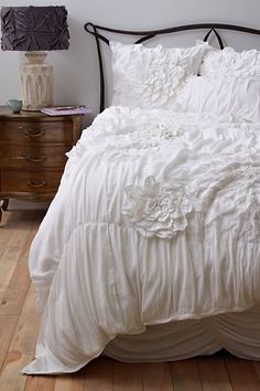 a white bed with ruffled bedspread and pillows