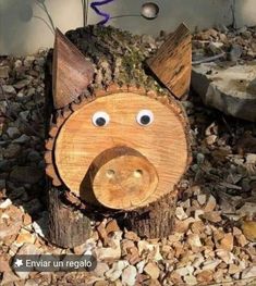 a wooden pig head sitting on top of a pile of rocks next to a tree