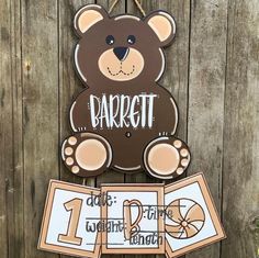 a brown teddy bear hanging from the side of a wooden fence with two signs on it