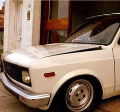 an old white car parked in front of a building