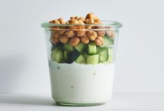 a glass jar filled with cucumbers and nuts on top of a white surface