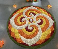 a colorful flower arrangement on the floor with candles around it and flowers in the background