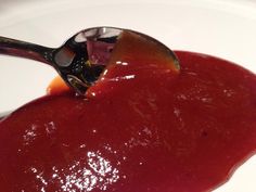 a spoon with some sauce on it sitting in a bowl