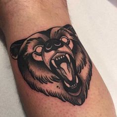 a bear tattoo on the arm with its mouth open