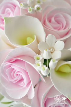 a bouquet of pink roses and white calla lilies with green leaves in the center