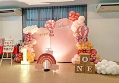 a room with balloons and decorations on the floor, including an arch that says one