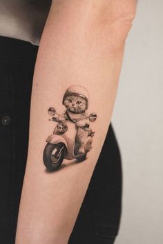 a person with a tattoo on their arm is riding a scooter and holding a teddy bear