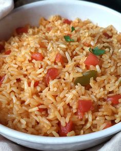 a white bowl filled with rice and veggies on top of a table cloth