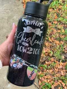 a person holding a black water bottle with the words cheerleader from 2 to 10 on it