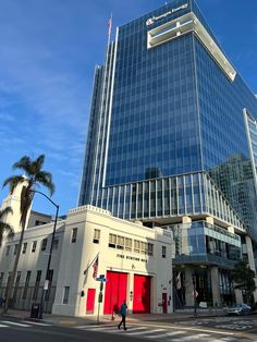 a tall building with a red door in front of it and palm trees on the side