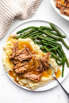 a white plate topped with mashed potatoes and green beans covered in gravy