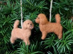 two felt poodle ornaments hanging from a christmas ornament on a pine tree