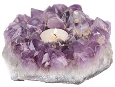 a candle that is sitting in some kind of rock with purple crystals around it on a white background