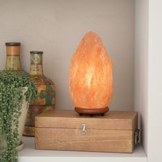 an orange himalayan stone sitting on top of a wooden box next to two vases