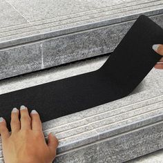 a woman is using a black tape to attach the edge of a stair treading