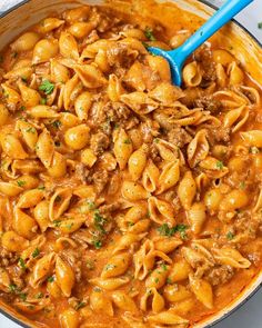 creamy beef and shells in a skillet with a ladle full of pasta sauce