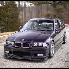 the purple car is parked on the side of the road in front of some trees