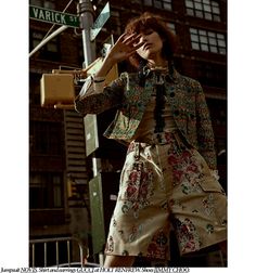 a woman standing on the side of a street next to a traffic light with her hand in her mouth