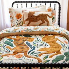 a bed with a tiger quilt on top of it next to two pillows and a pillow case