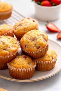 several muffins on a plate with strawberries in the background