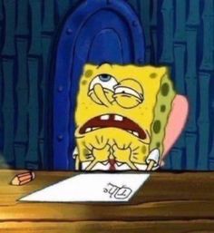 spongebob sitting at a desk in front of a piece of paper