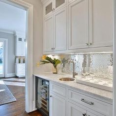 a kitchen with white cabinets and wood floors