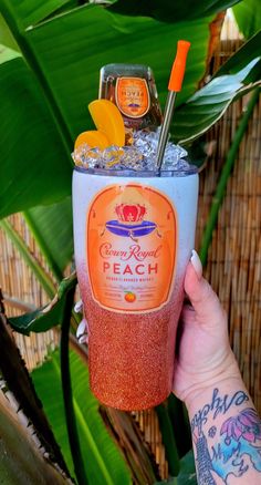 a person holding up a drink in front of some plants