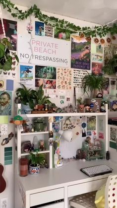 there is a desk with many plants and pictures on the wall