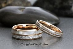 two wedding bands are sitting next to each other on a table with rocks in the background